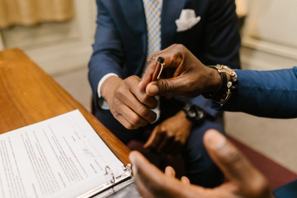 Two businessmen in suits finalize a contract, highlighting teamwork and agreement.